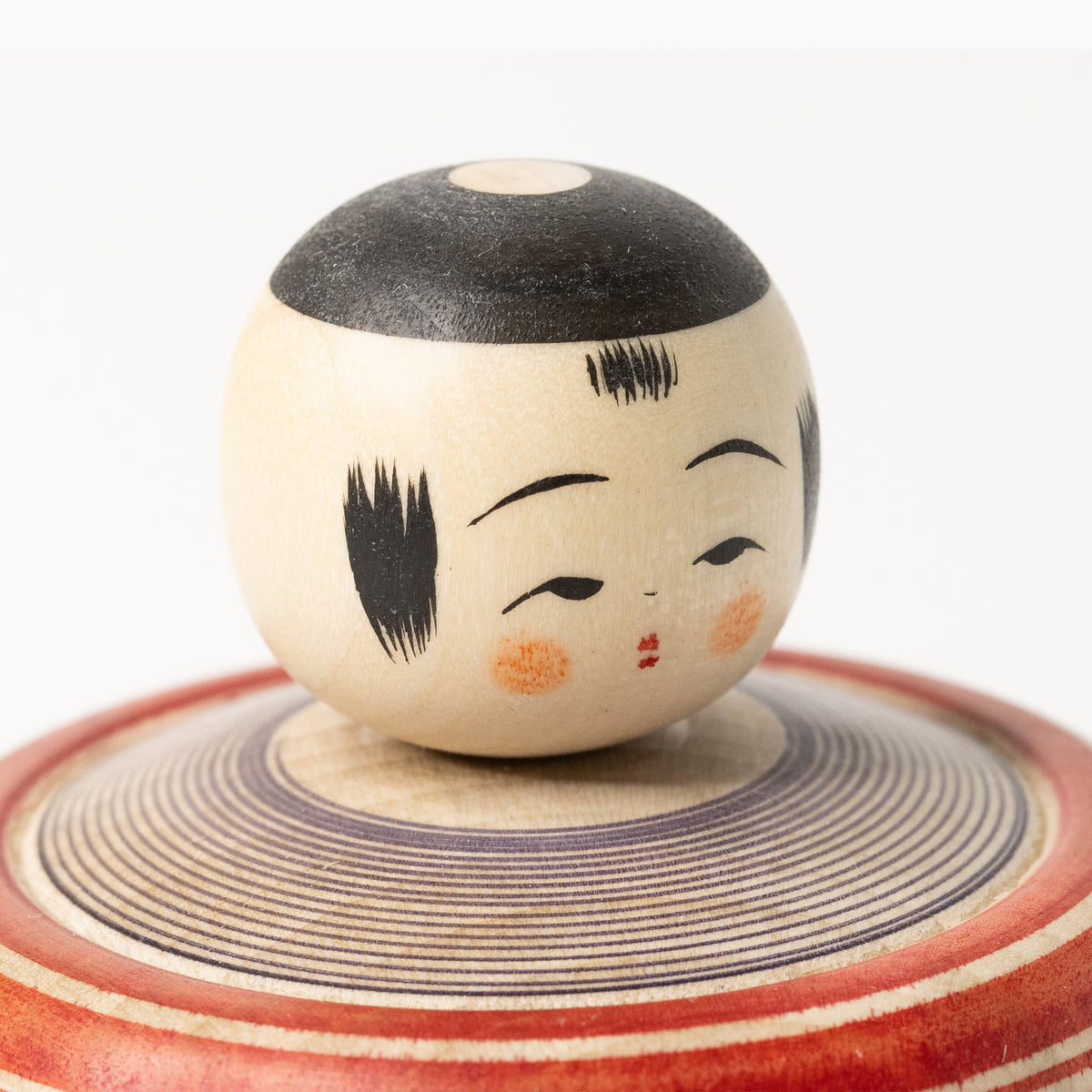 Facial detail of the Makoto-style Ejiko kokeshi in red and indigo