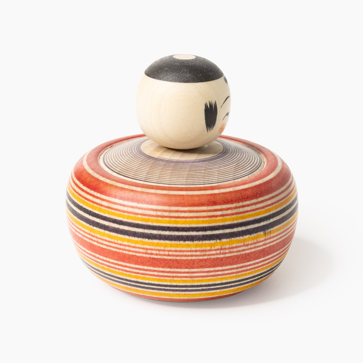 Ejiko kokeshi with red and indigo lathe-painted rings in three-quarter rear view