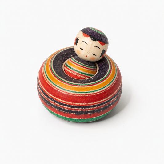 Ejiko-Kokeshi mit rot-schwarzem Makoto-Muster in schräger Vorderansicht